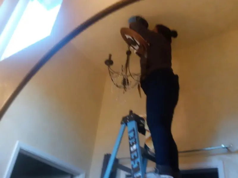 Electrician installing a chandelier in a Sonora residence